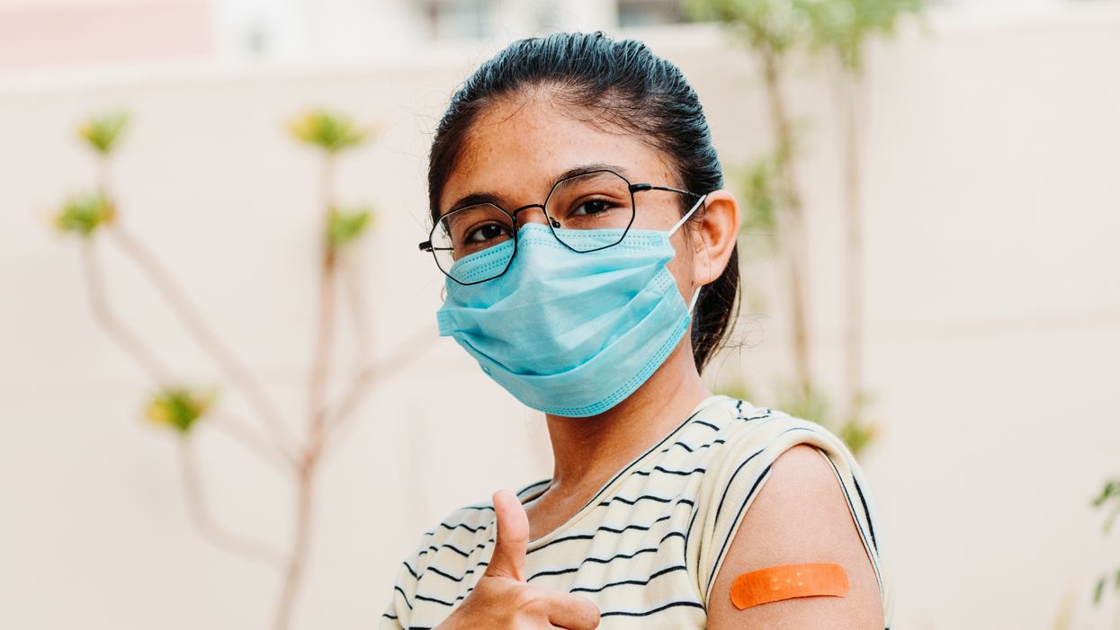 Portrait of a teen giving thumbs up after getting vaccinated and showing bandage on her arm